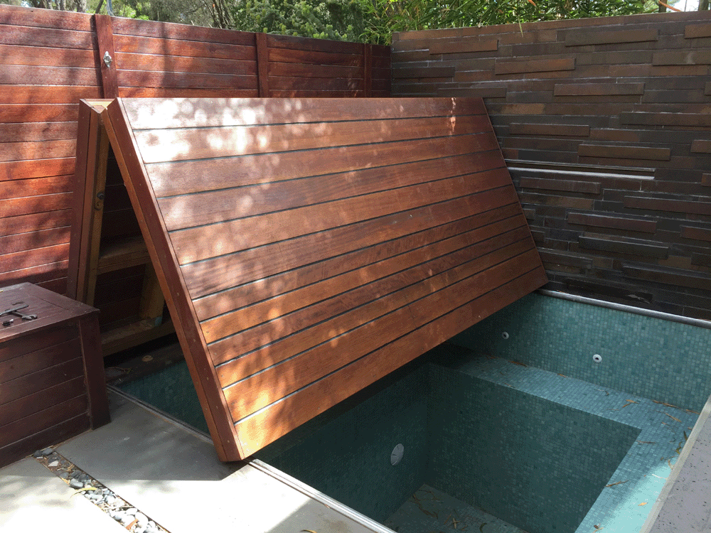 Custom plunge pool cover system mid-lift revealing the water below